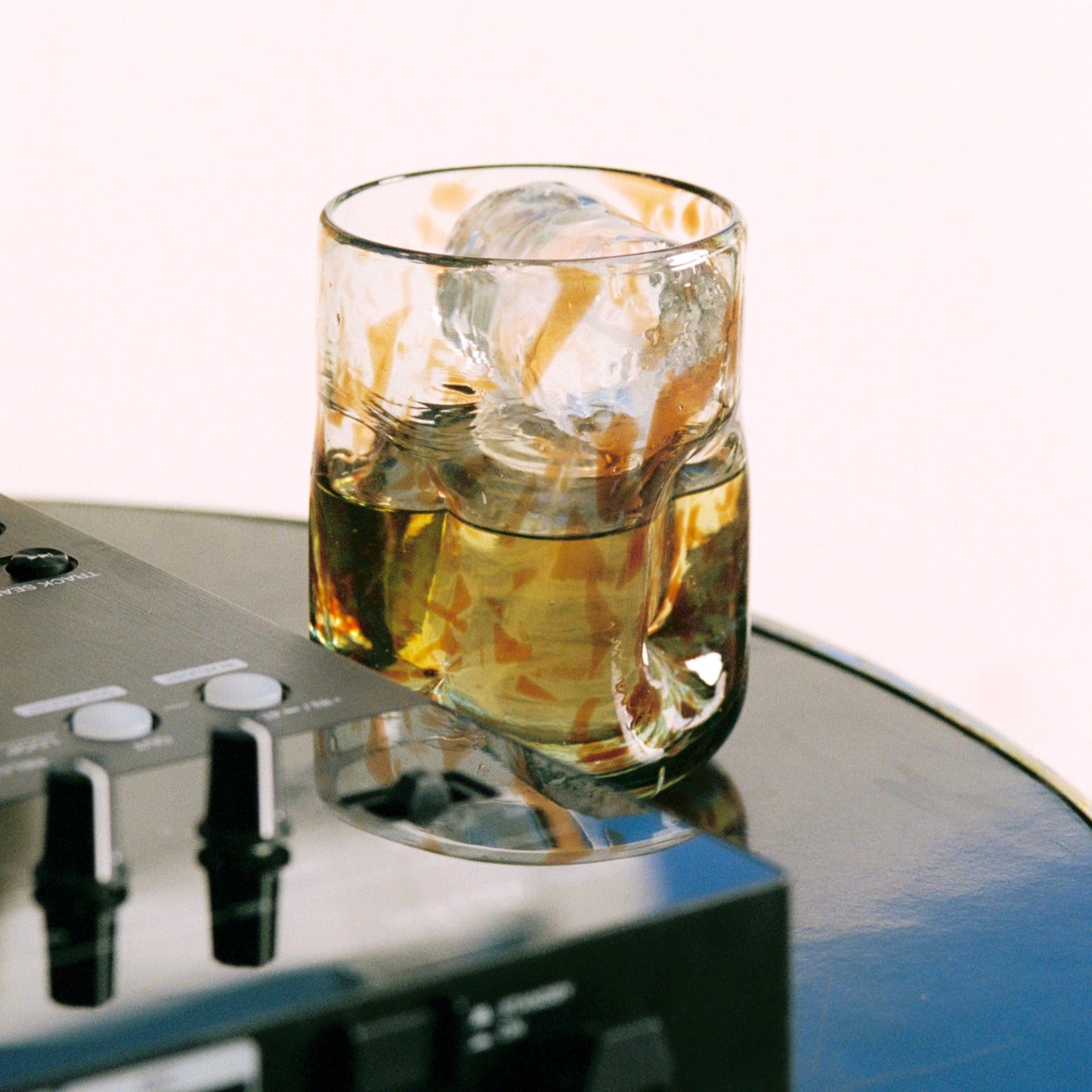 DeflatedGlass of whisky with ice cubes on a turntable - lifestyle