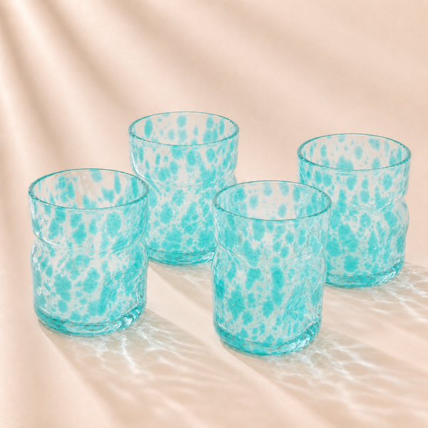 Four turquoise deflated glasses with a marbled pattern on a beige surface