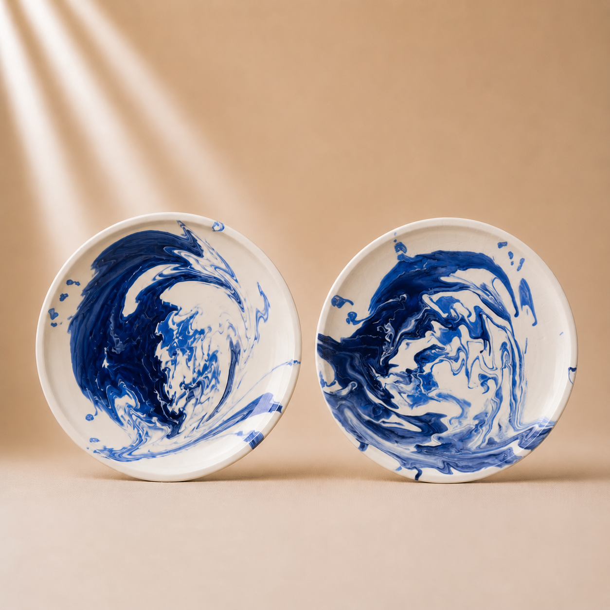 Two ceramic plates with blue and white abstract patterns on a beige background