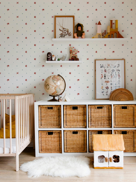 Children's room with crib, storage baskets, and decorative items against a star-patterned wallpaper by Lizzet Frausto.
