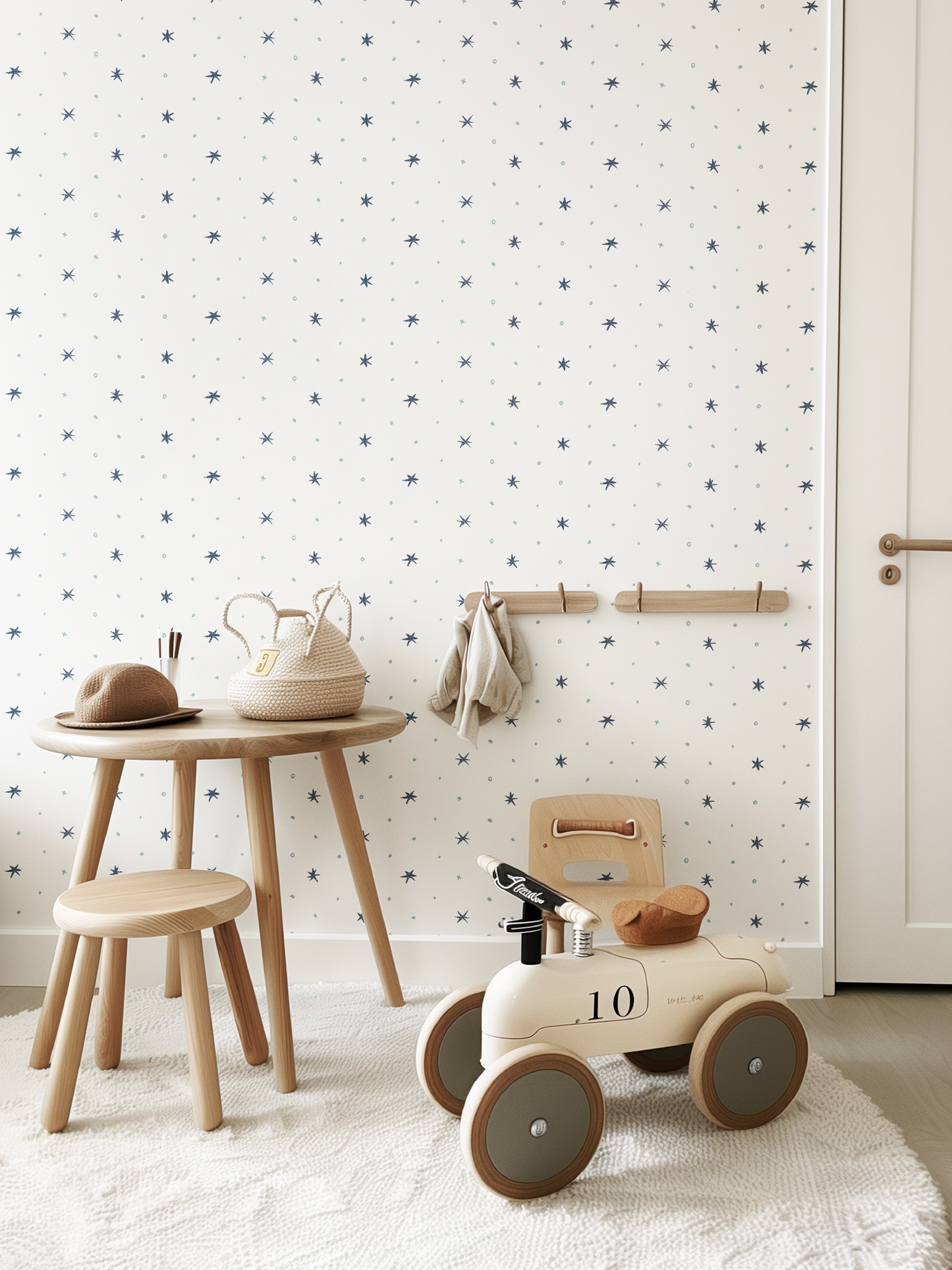 Children's toy car with wheels in a playroom with wooden furniture and patterned star wallpaper designed by Lizzet Frausto.