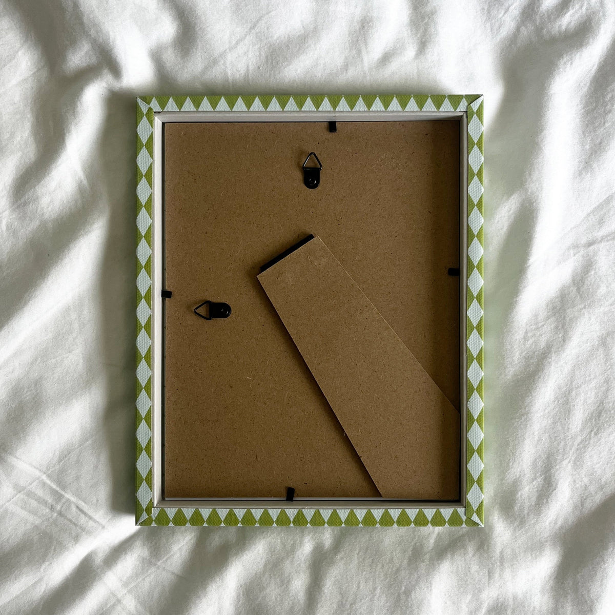 back view of a handmade patterned fabric picture frame showcasing wall fittings and frame structure