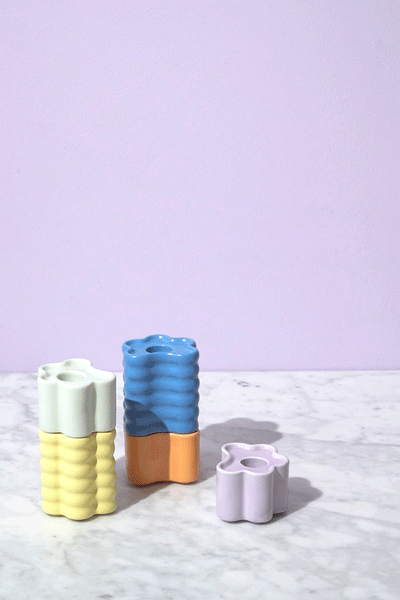 Three pastel Octaevo Flora Candle Holders are arranged on marble, set against a light purple backdrop.
