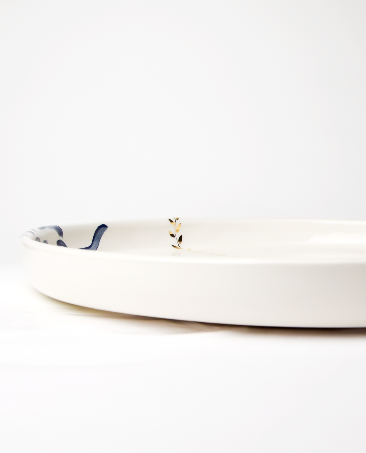 A ceramic serving platter with a royal blue floral pattern and gold accents on the edges.
