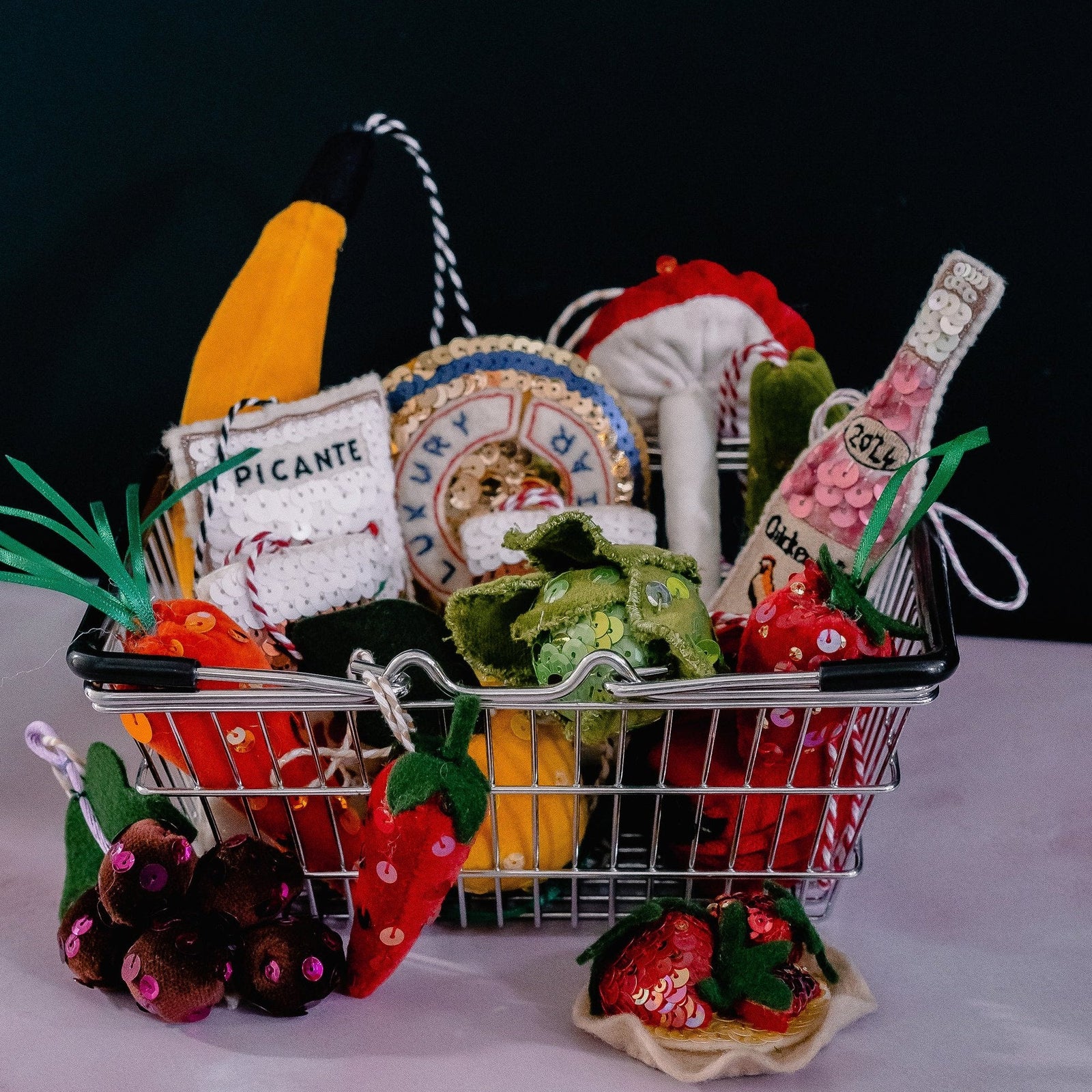 A small shopping basket filled with sequin ornaments of groceries