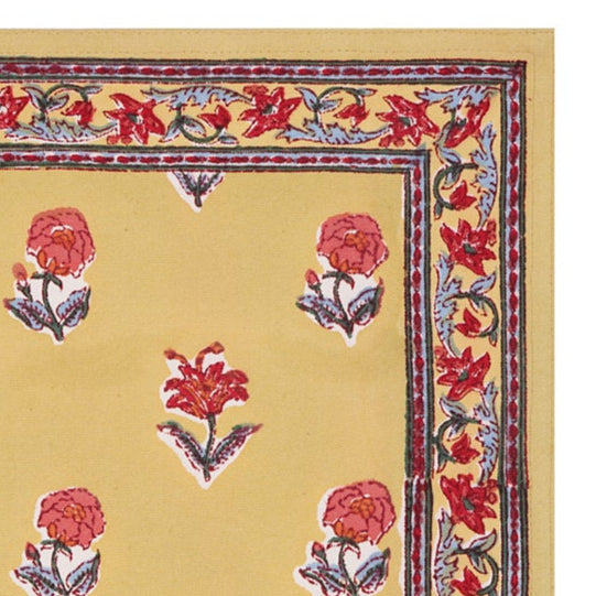A hand-block printed yellow cotton table mat with red floral patterns and blue border.
