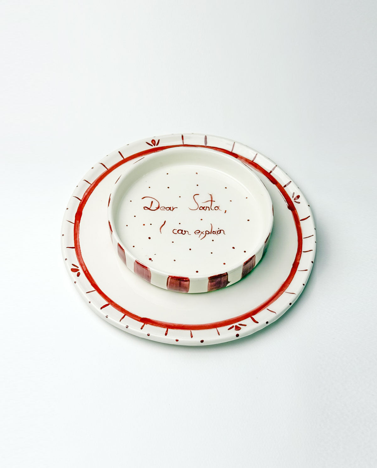 Set of Christmas ceramic plates with red and white design on a white background