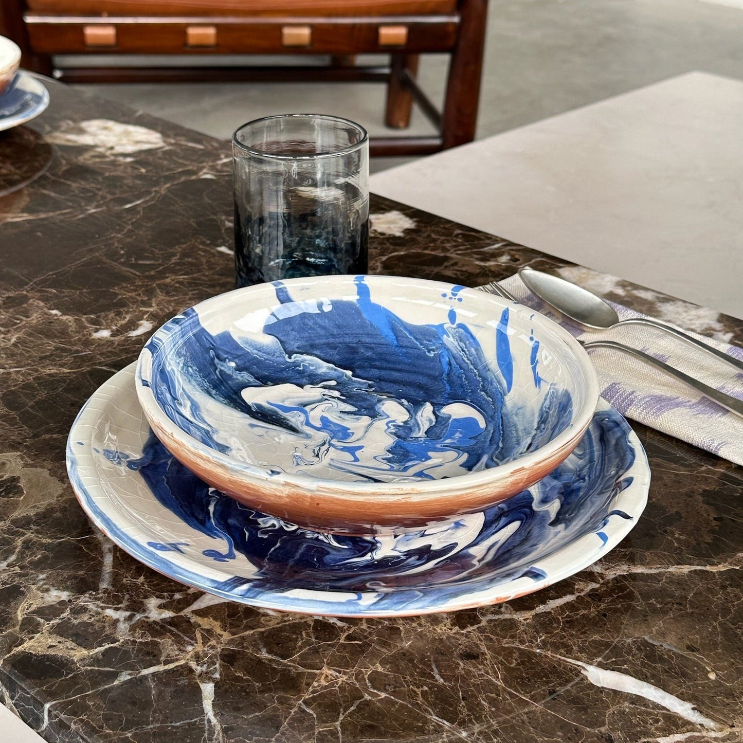 Blue and white ceramic bowl on a marble surface with a brown leather chair in the background. - lifestyle