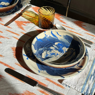 Dining table setting with blue and white ceramic plates on a patterned tablecloth. - lifestyle