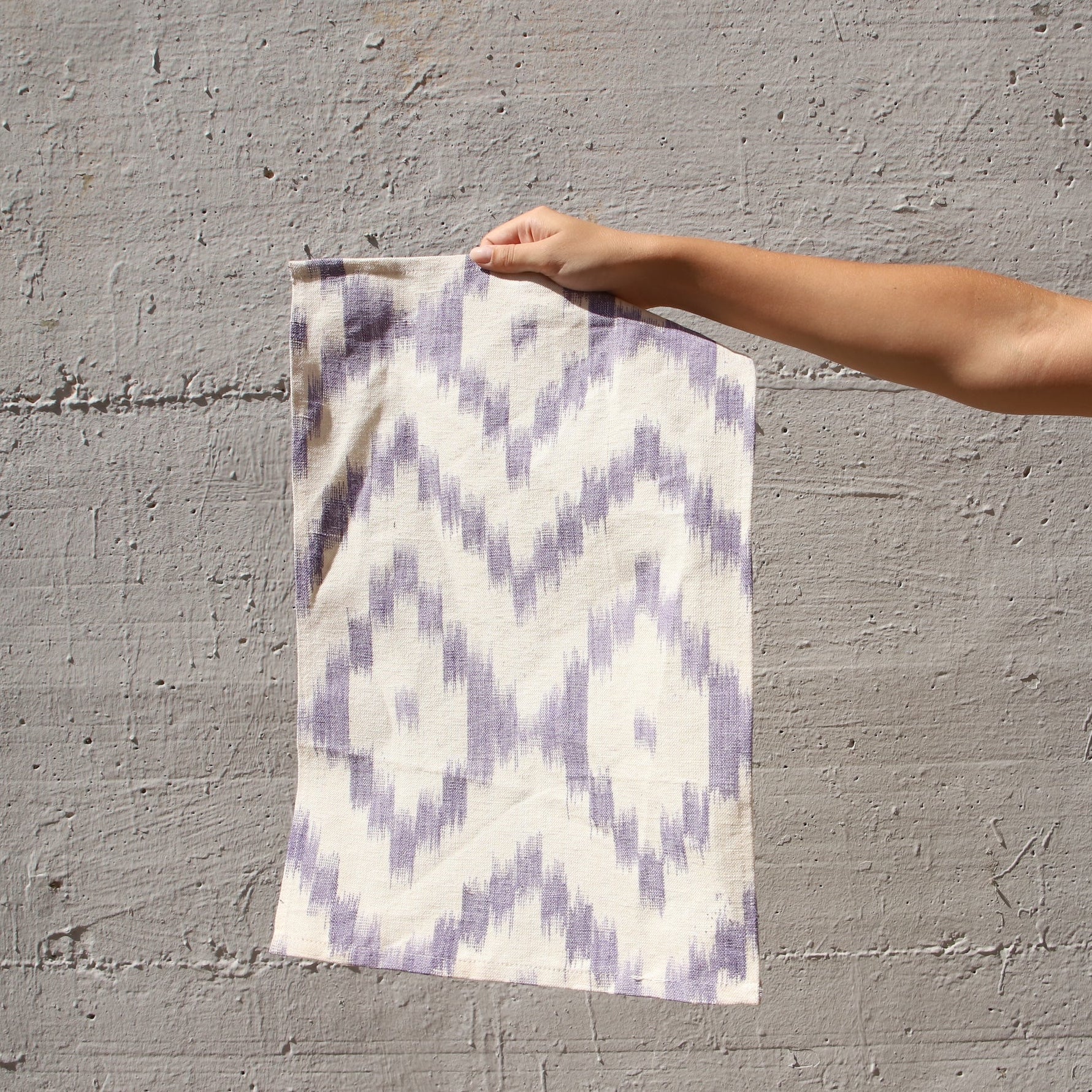 Person holding a patterned linnen against a gray wall - lifestyle