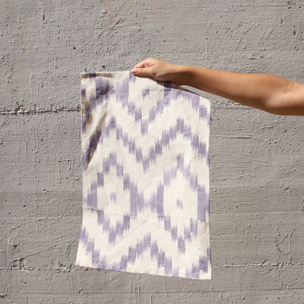 Person holding a patterned linnen against a gray wall - lifestyle