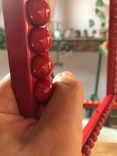 Hand holding Crimson Red Bobbin Frame