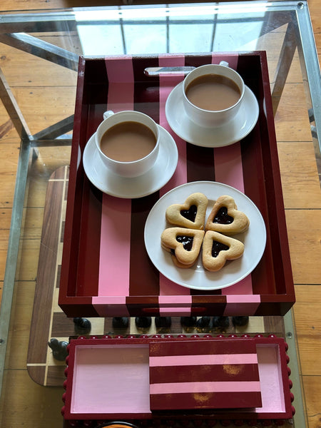 Table setting with cookies, cups, and a candle on a glass table.