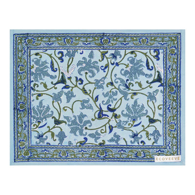 A rectangular cotton table mat with a floral hand-block print in blue, green, and white colors.