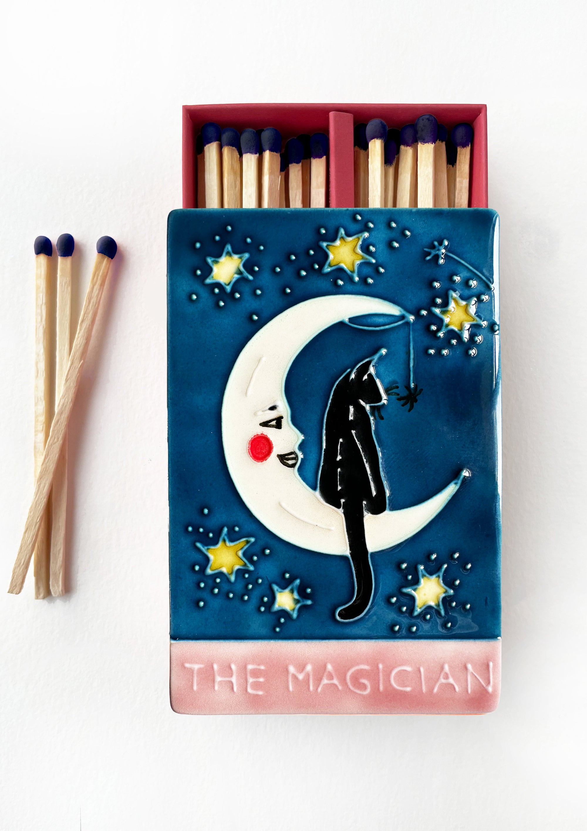 Luxury ceramic matchbox featuring The Magician Tarot card - a black cat sits within a crescent moon. The ceramic artwork sits atop a luxury card case with striker strip. Each box contains 40 navy coloured extra long safety matches.