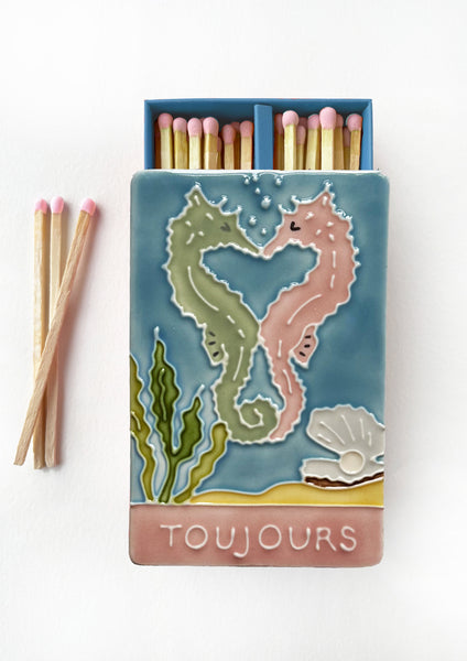 Luxury ceramic matchbox featuring kissing seahorses. The ceramic artwork sits atop a luxury card case with striker strip. Each box contains 40 peach coloured extra long safety matches.