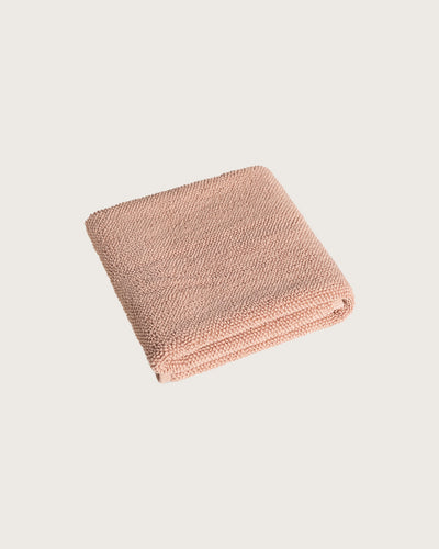 Folded pink bathmat on a light beige background