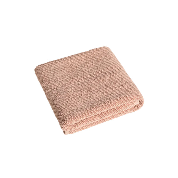 Folded pink bathmat on a light beige background