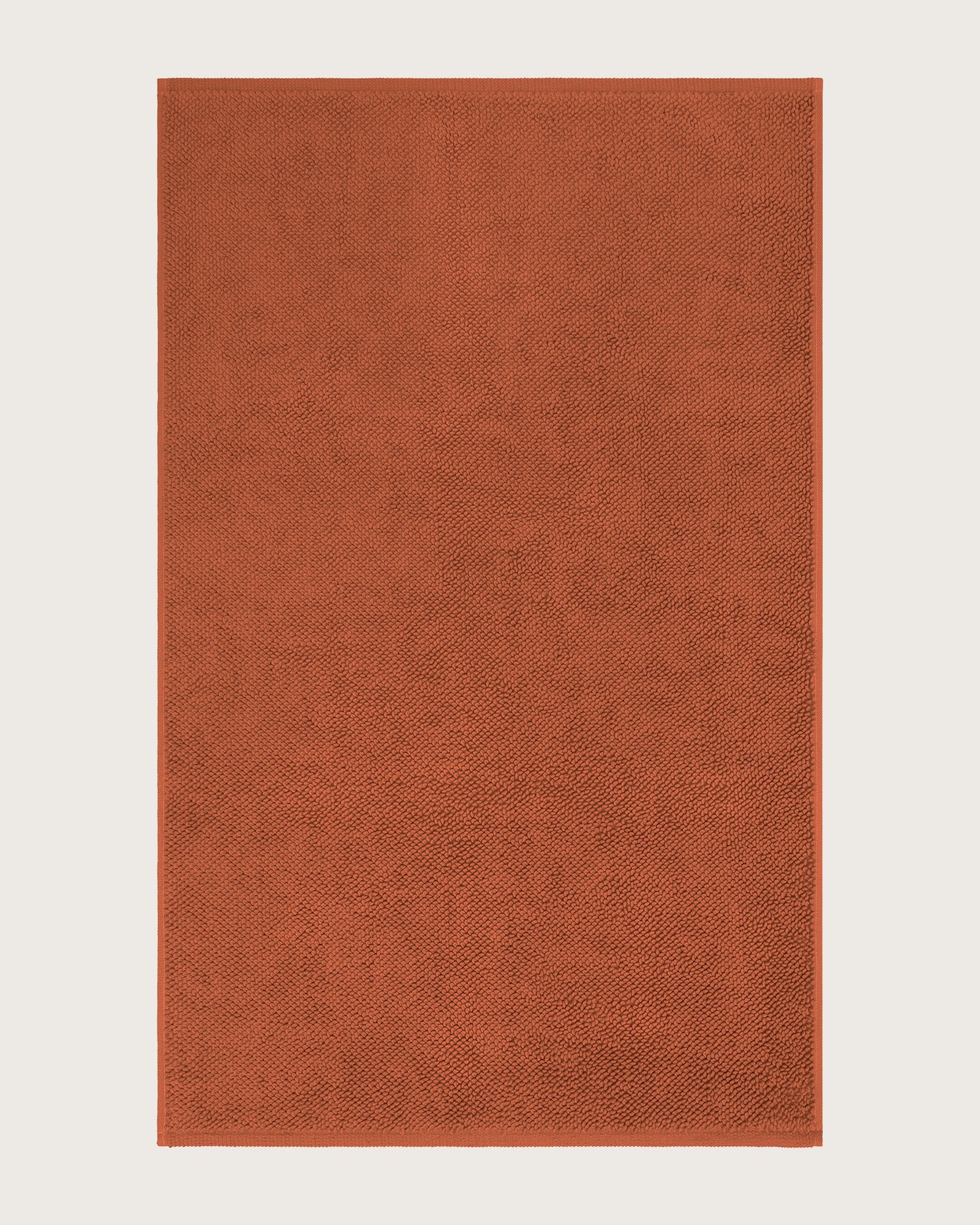 Rectangular orange bathmat on a light beige background