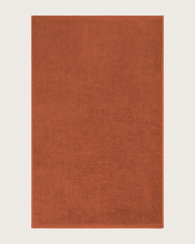 Rectangular orange bathmat on a light beige background