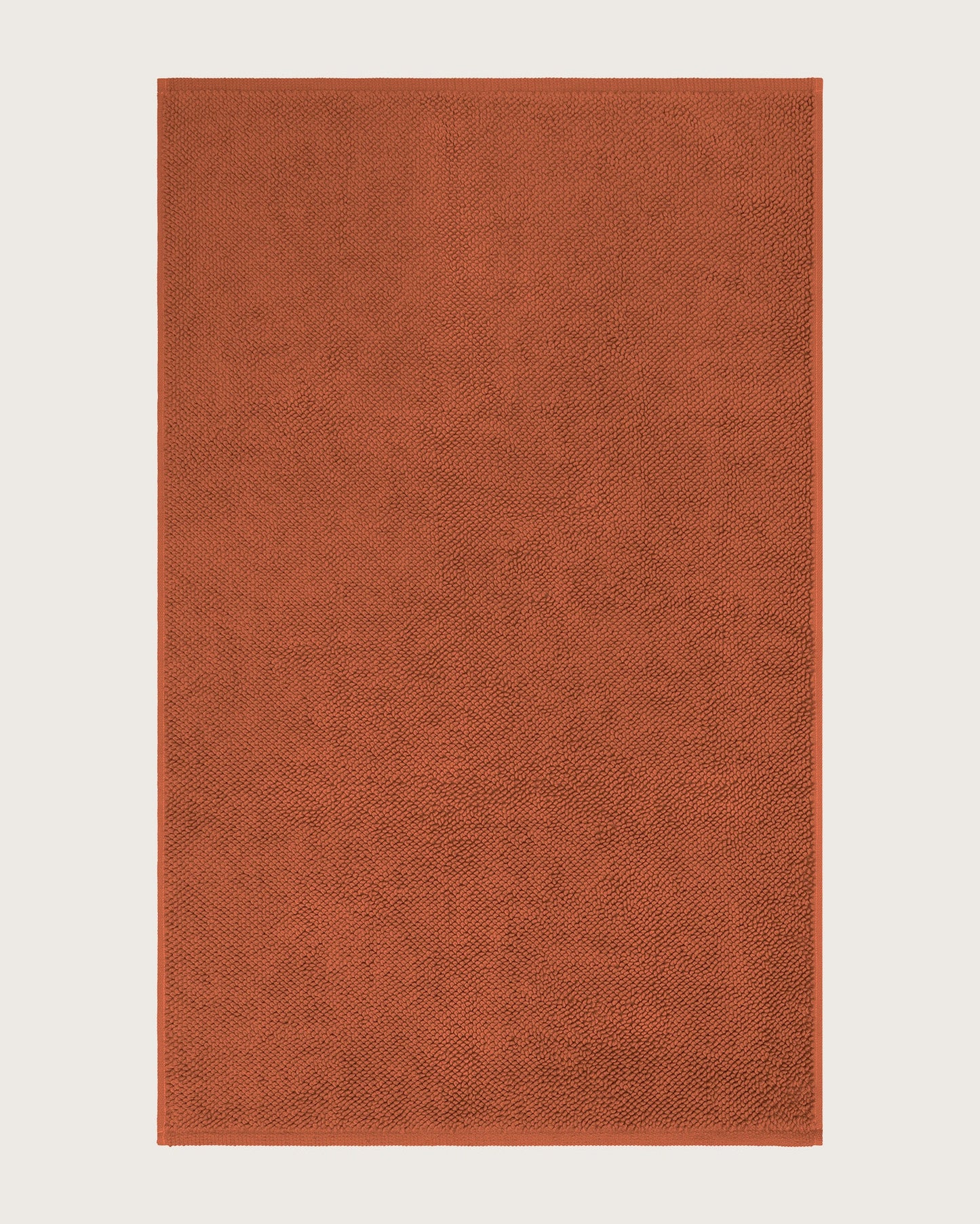 Rectangular orange bathmat on a light beige background
