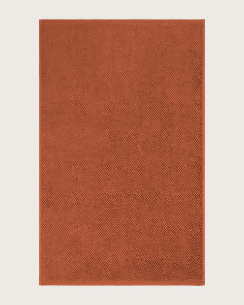 Rectangular orange bathmat on a light beige background