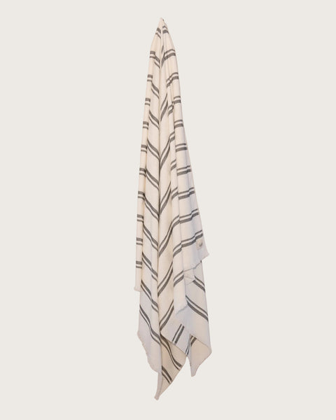 Kobn Crema towel with black stripes hanging on a butter yellow background