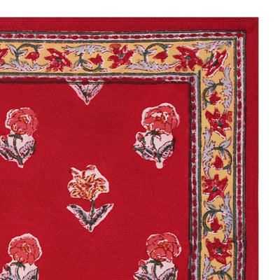 A hand-block printed red cotton table mat with floral patterns and a border.