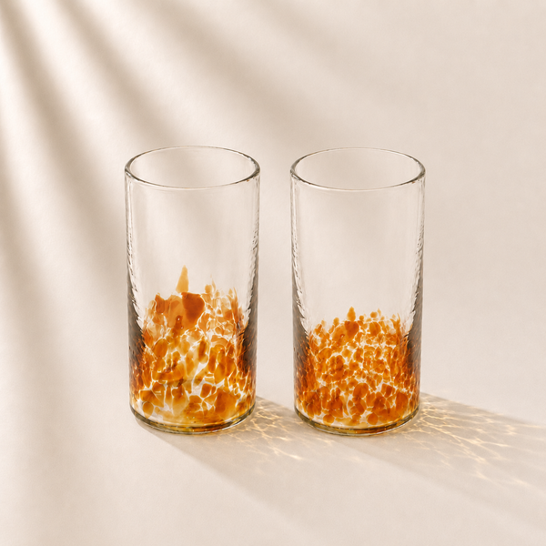 Two clear glasses with orange interior patterns on a beige background
