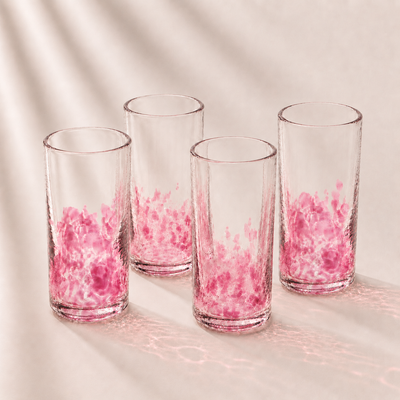 Four clear glasses with pink interior patterns on a light background