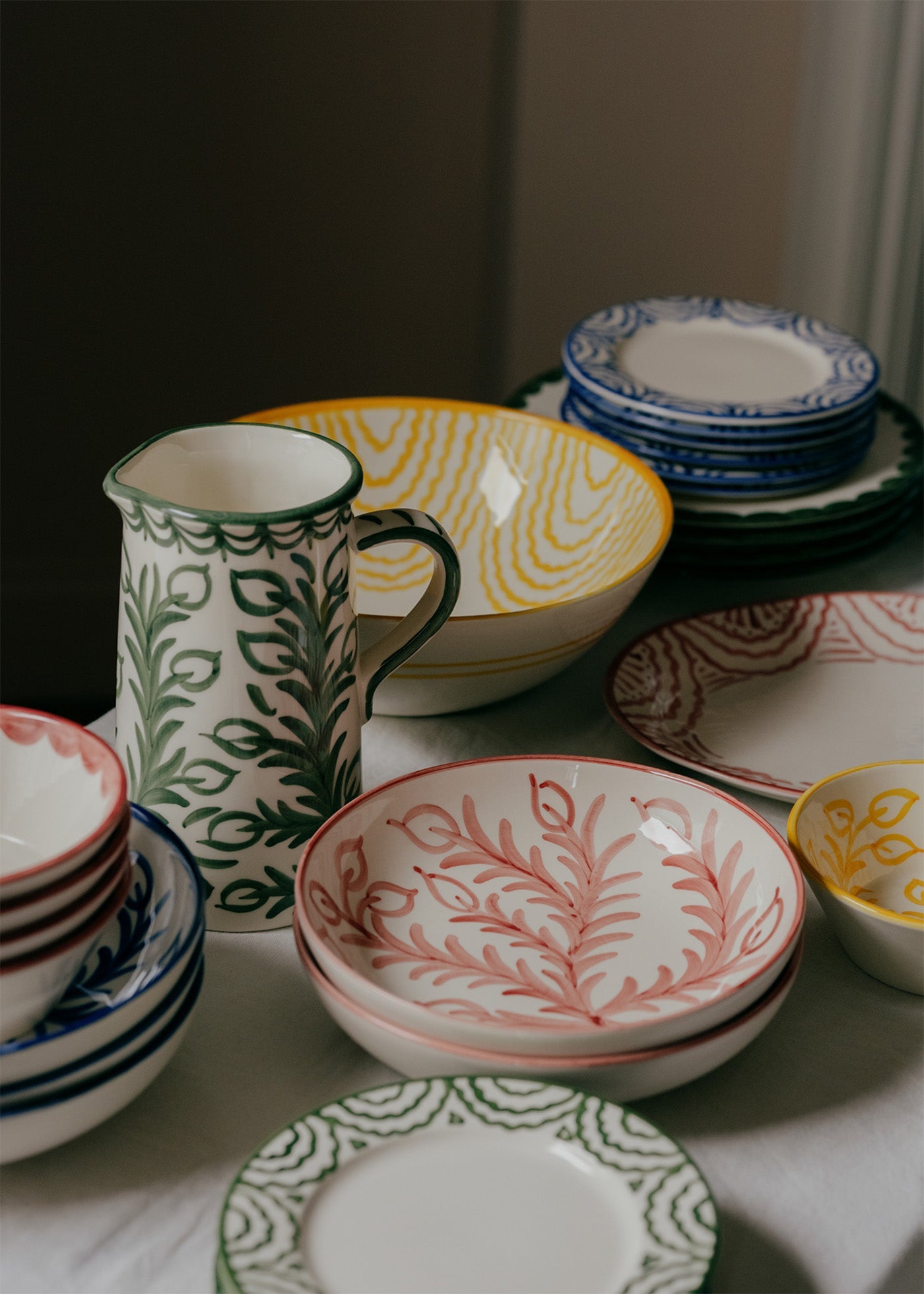 Collection of patterned ceramic dishes including bowls and a pitcher on a neutral background