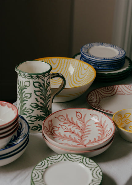 Collection of patterned ceramic dishes including bowls and a pitcher on a neutral background