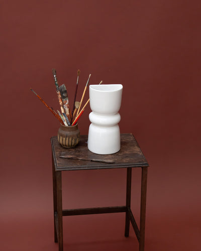 White ceramic decorative wall sconce on a wooden table with a brown background