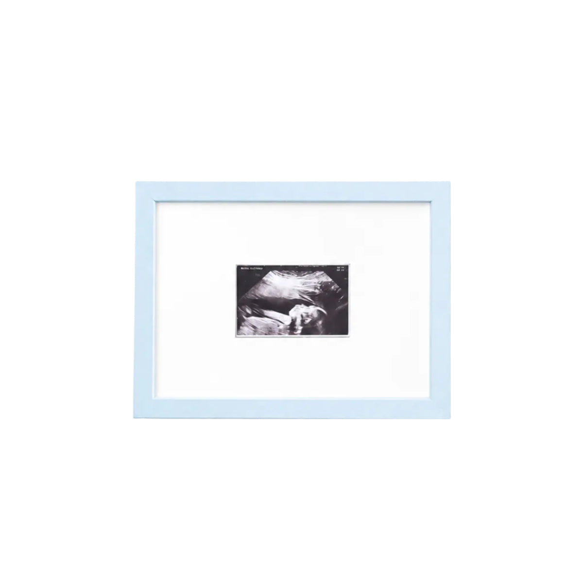 A square light blue picture frame with a white mat, containing a small black-and-white photograph, shown hanging on a plain white wall.