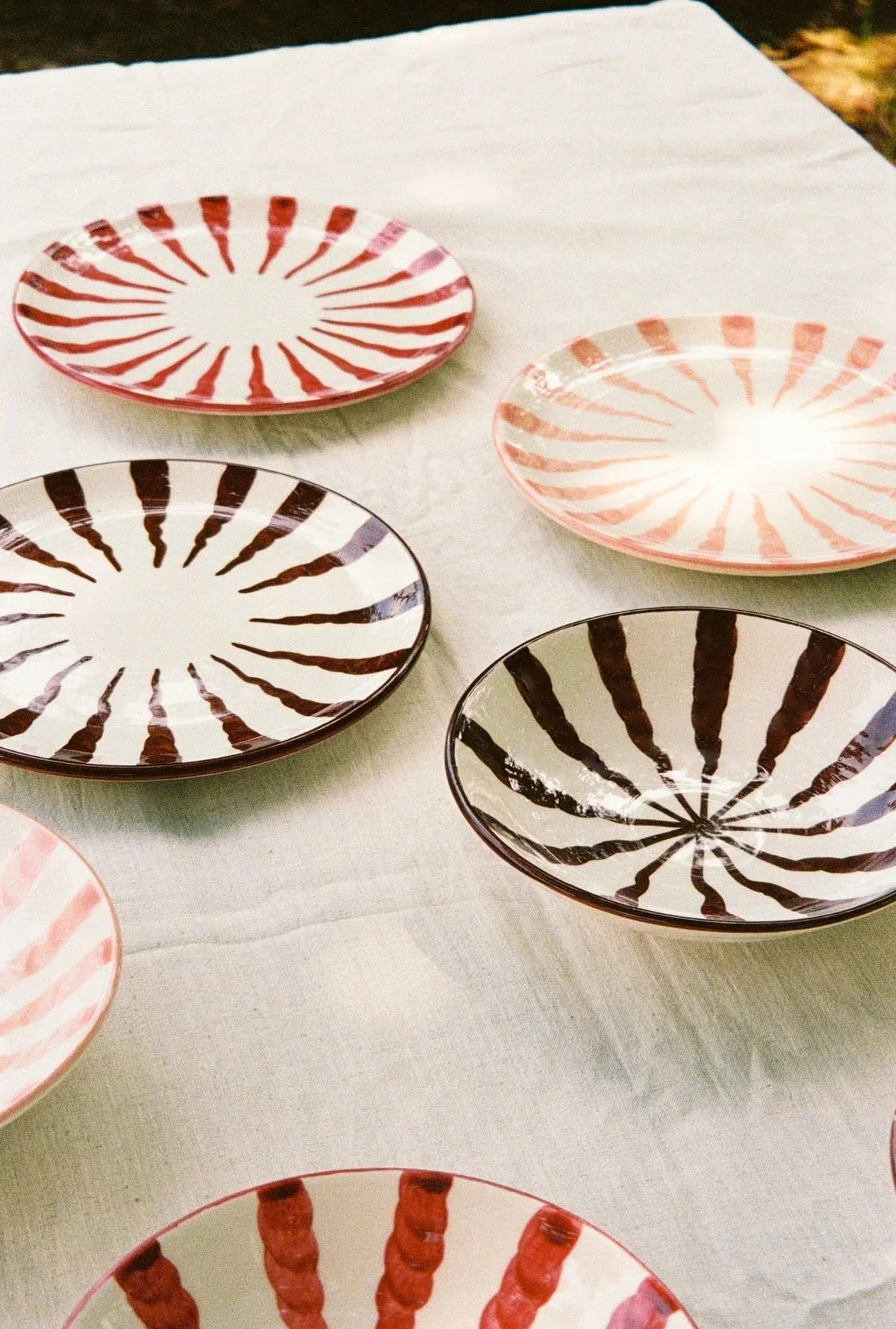 Set of ceramic plates with striped patterns on a white cloth.