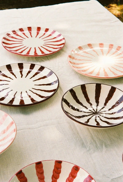 Set of ceramic plates with striped patterns on a white cloth.