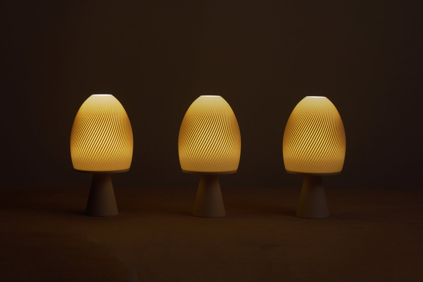Three mushroom-shaped lamps emitting a warm glow on a dark background