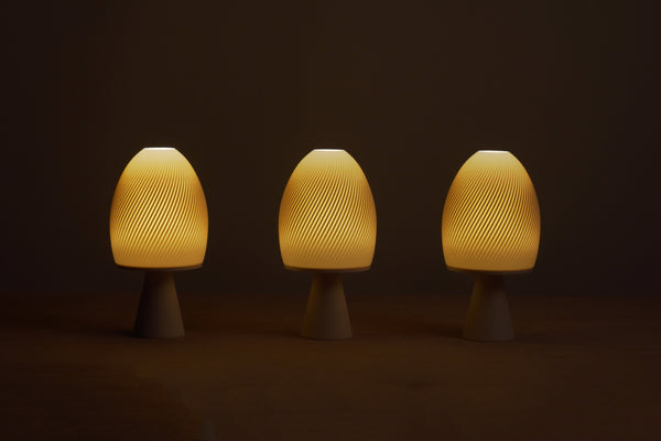 Three mushroom-shaped lamps emitting a warm glow on a dark background