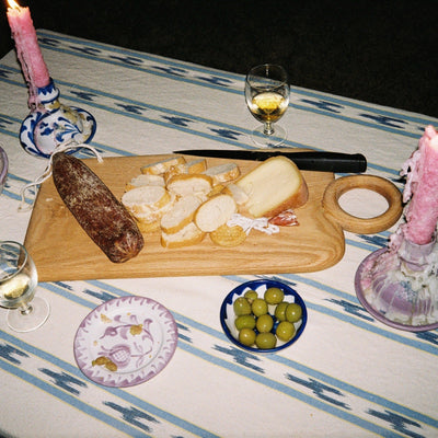 Table setting with a charcuterie board, candles, and wine glasses on a striped tablecloth. - lifestyle