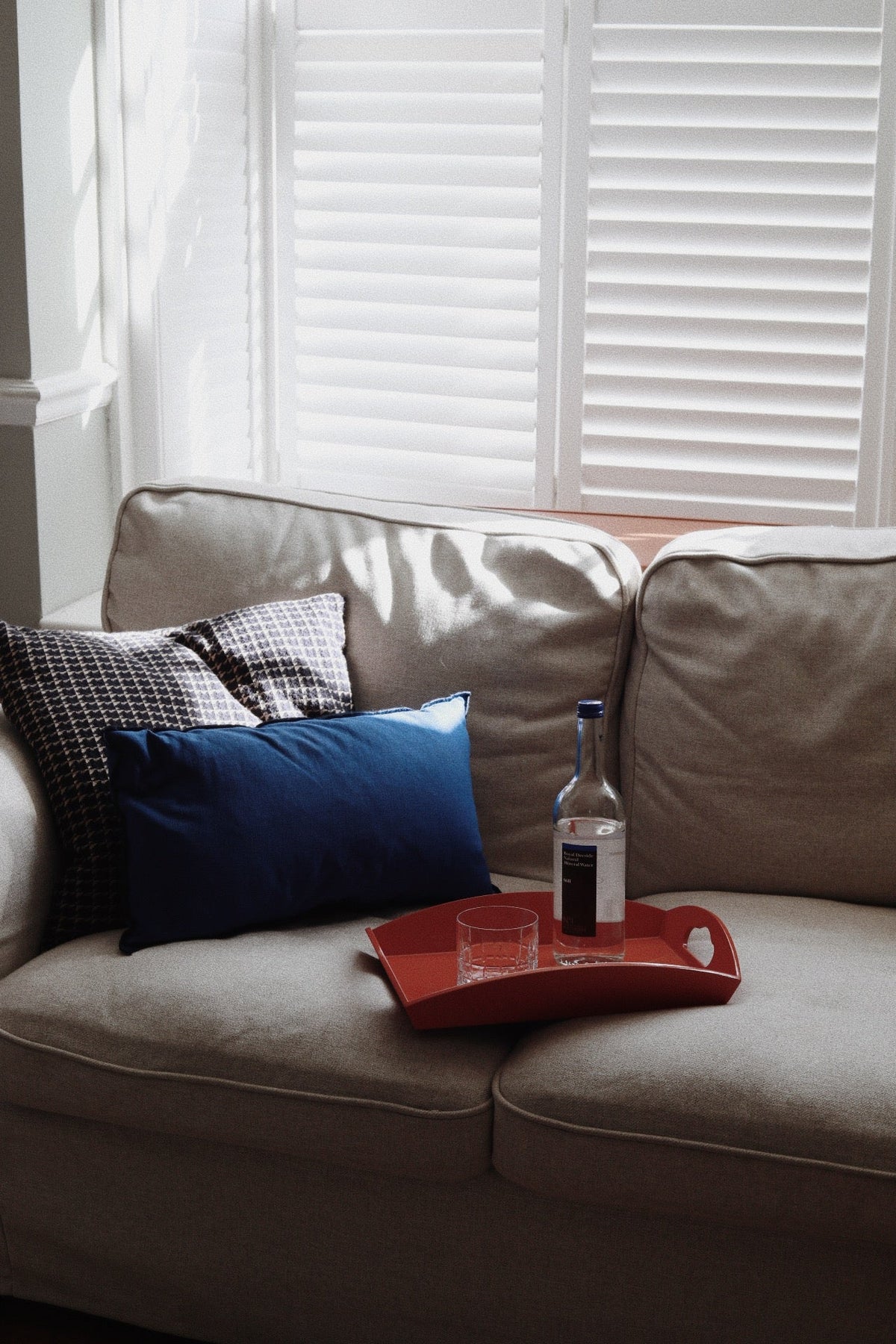 Vinidec medium red lacquered serving tray with handles styled on sofa with drinks bottle and glass