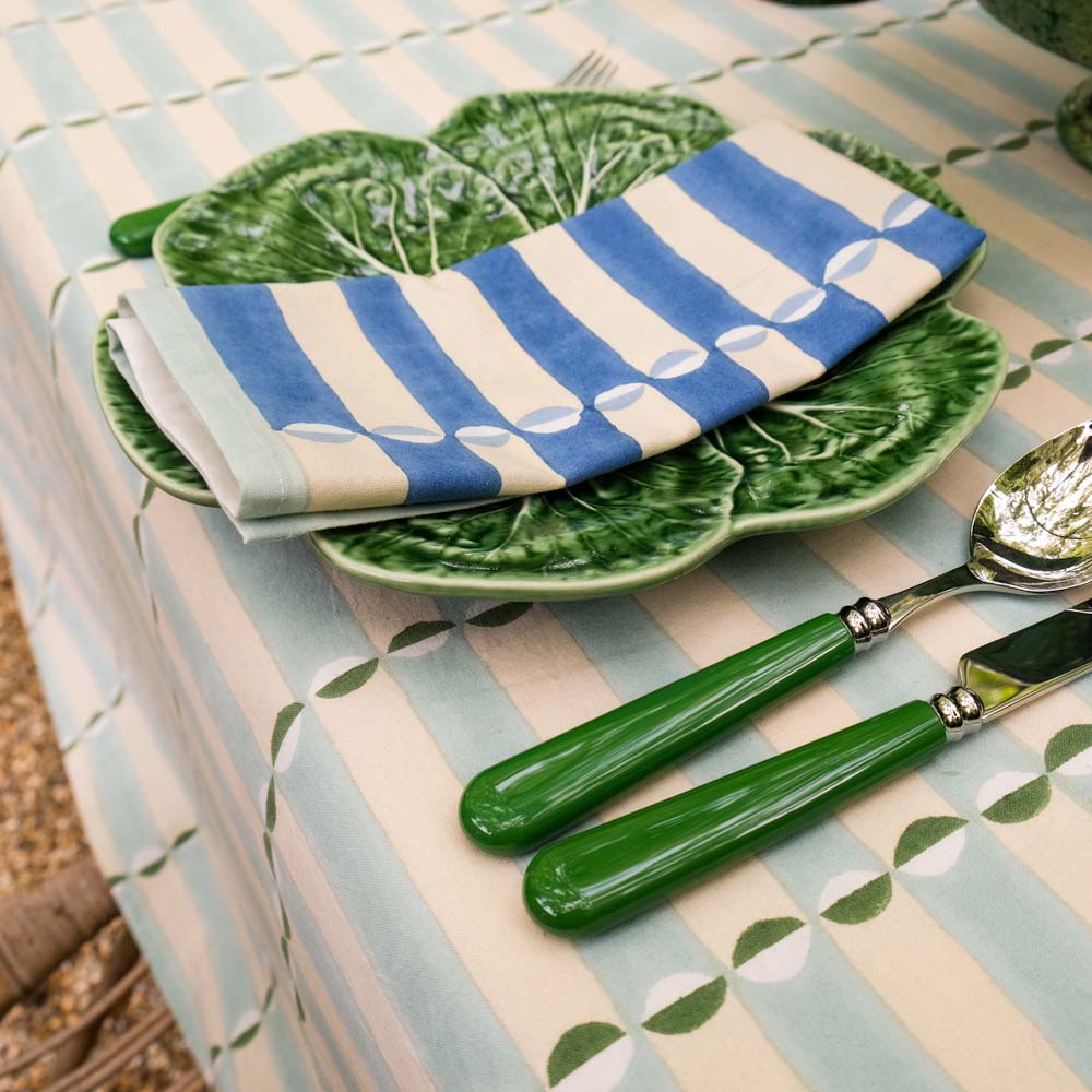Green ceramic plates with striped napkins on a patterned tablecloth