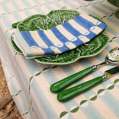 Green ceramic plates with striped napkins on a patterned tablecloth