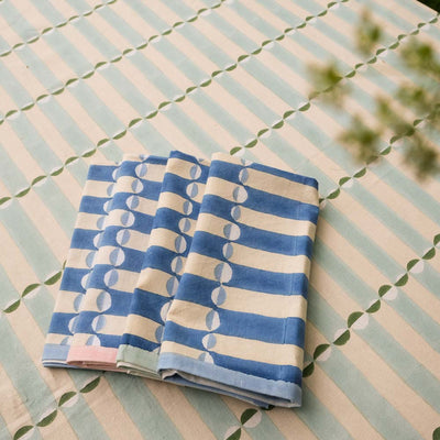 Folded blue and white striped luna napkin on a striped luna tablecloth.