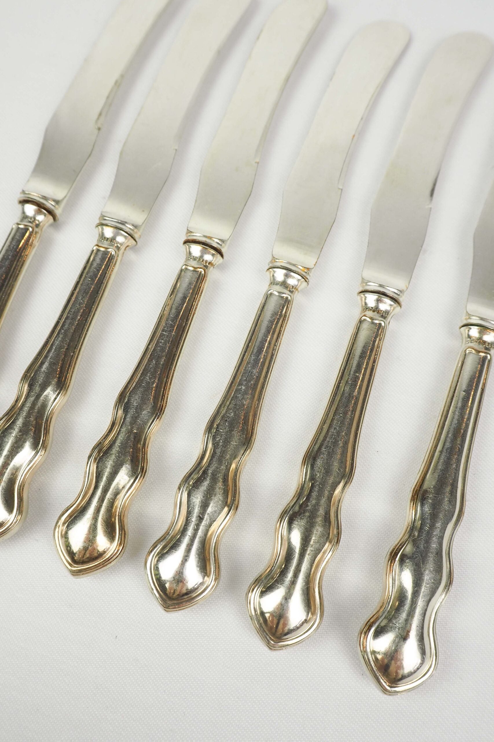 An Antique set of six Silver Plate Butter Knives with shapely tactile handles. 