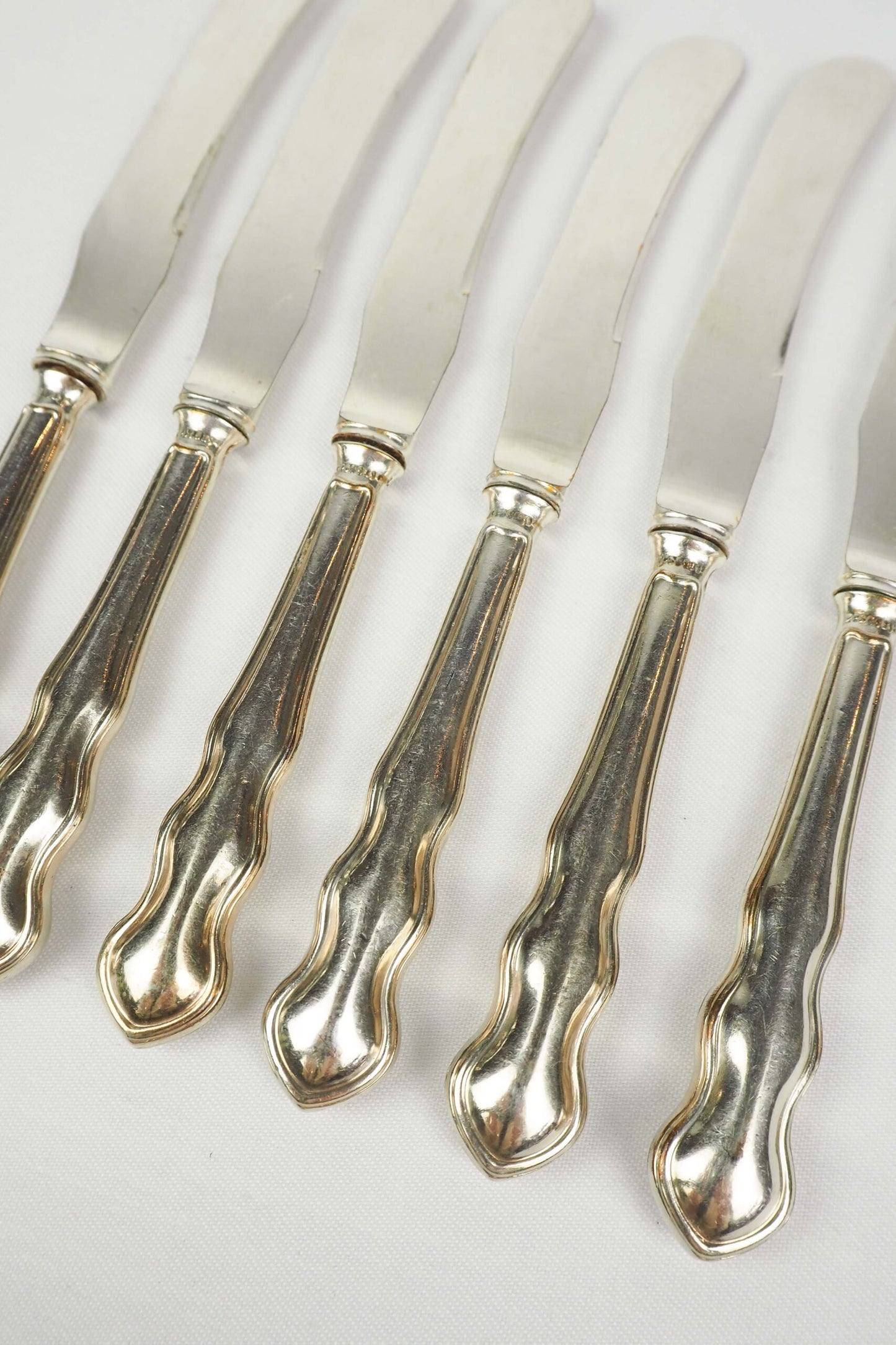 An Antique set of six Silver Plate Butter Knives with shapely tactile handles. 