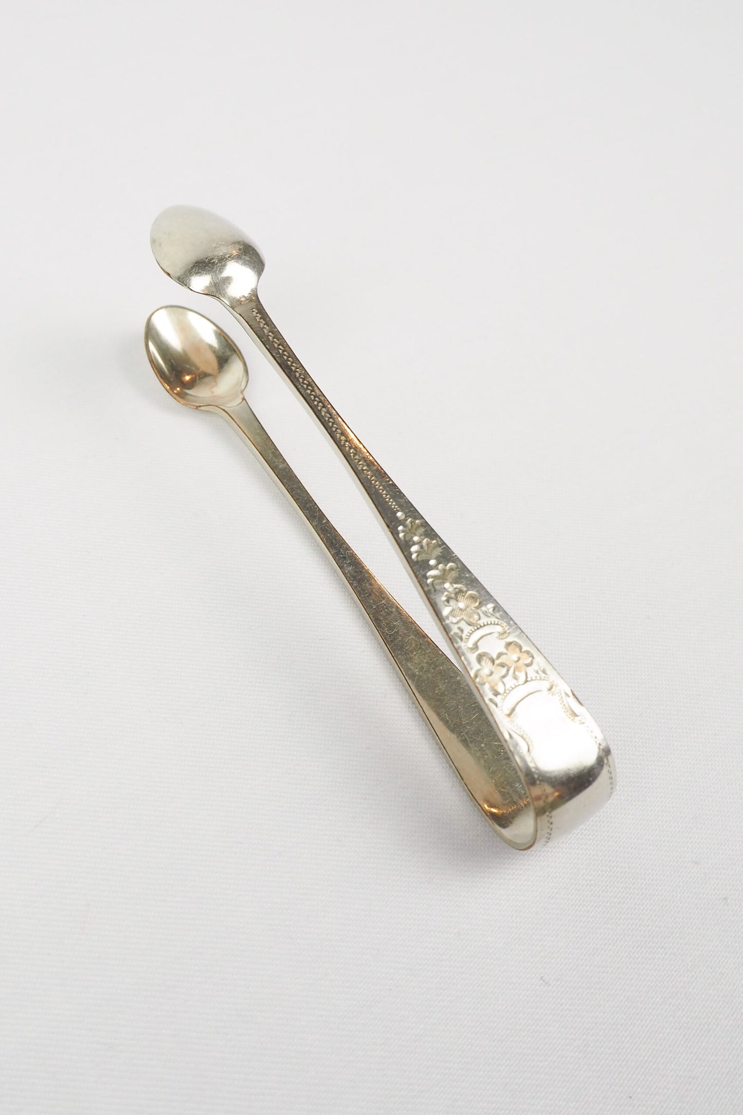 This Vintage Set of Silver Plate Sugar Tongs have a vintage stone washed patina to the silver plate and a decorative etched floral pattern. 