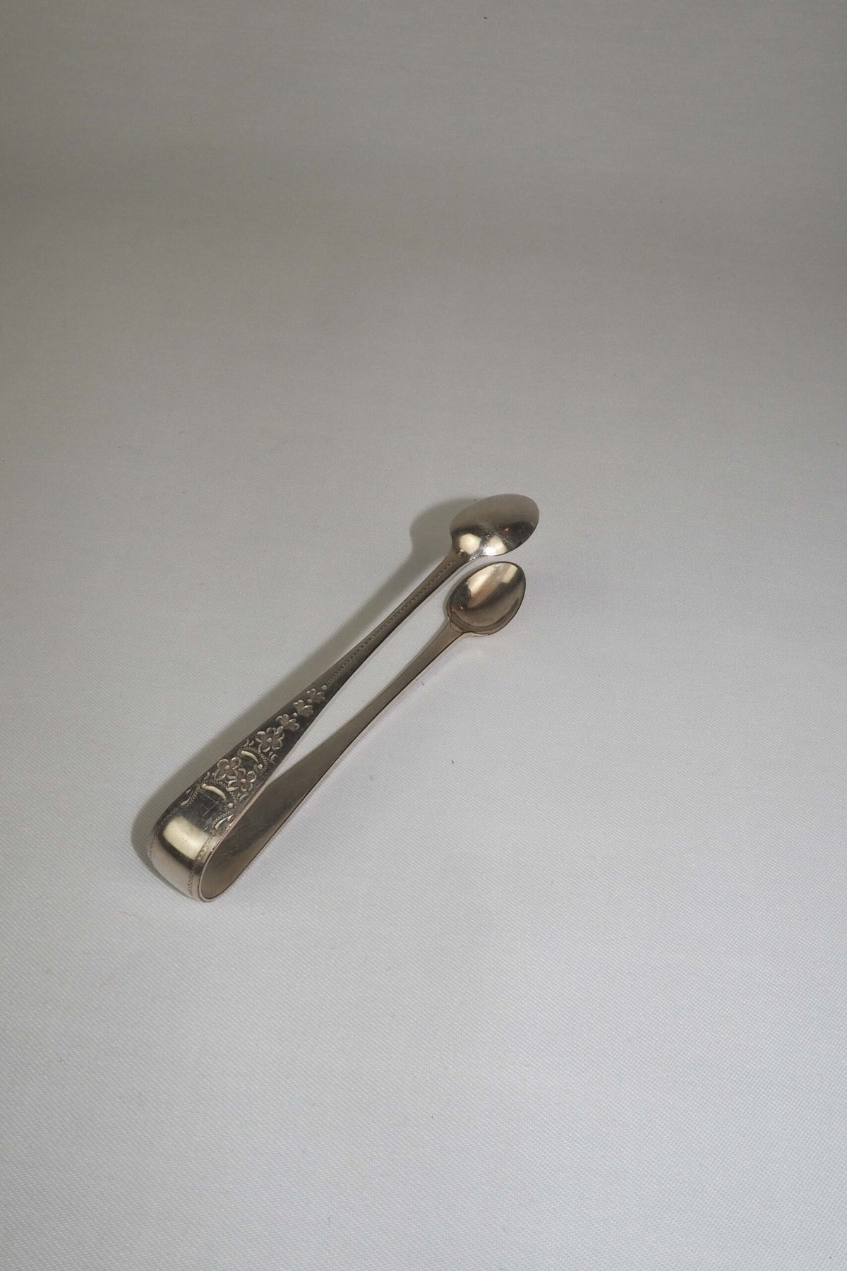 This Vintage Set of Silver Plate Sugar Tongs have a vintage stone washed patina to the silver plate and a decorative etched floral pattern. 
