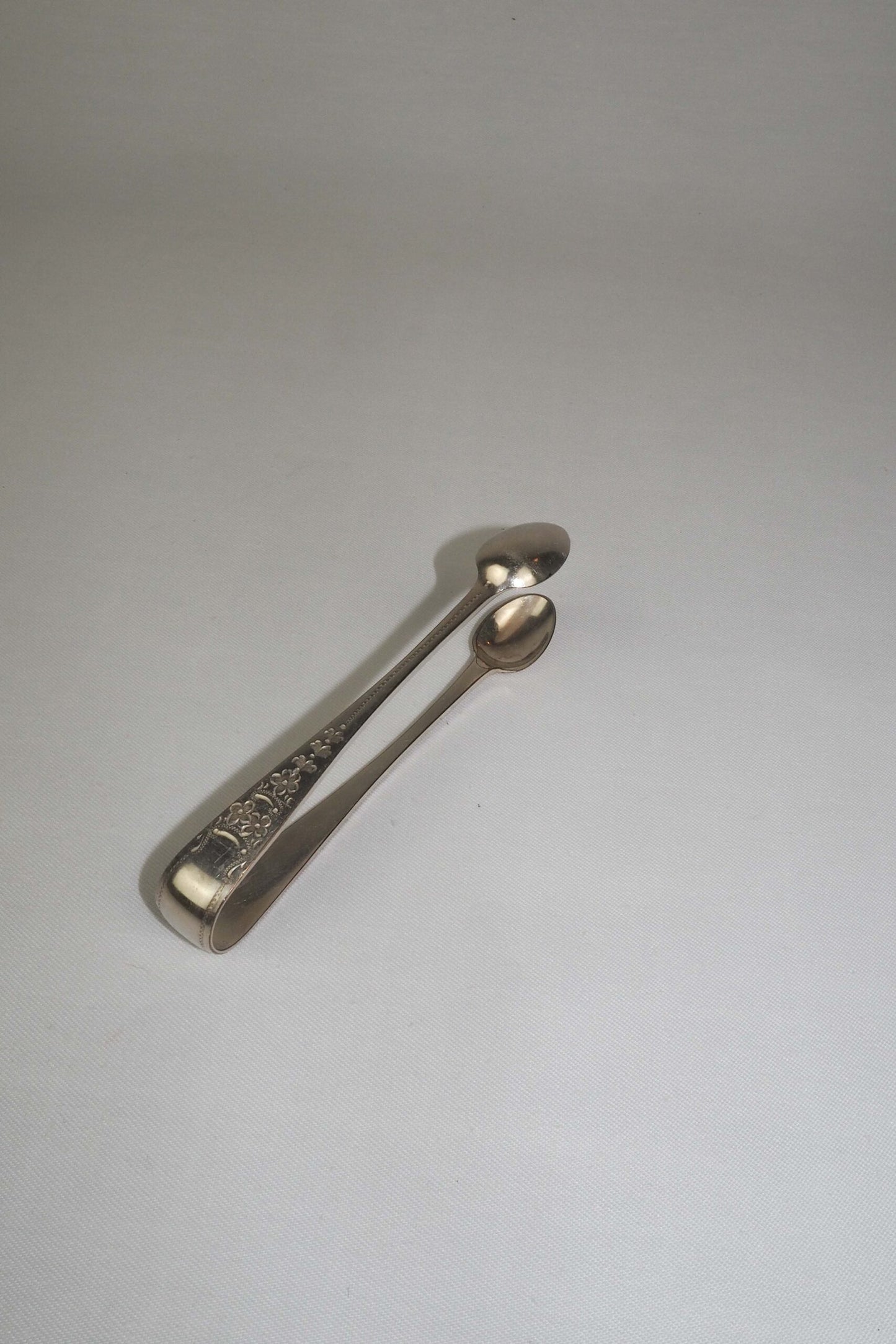 This Vintage Set of Silver Plate Sugar Tongs have a vintage stone washed patina to the silver plate and a decorative etched floral pattern. 