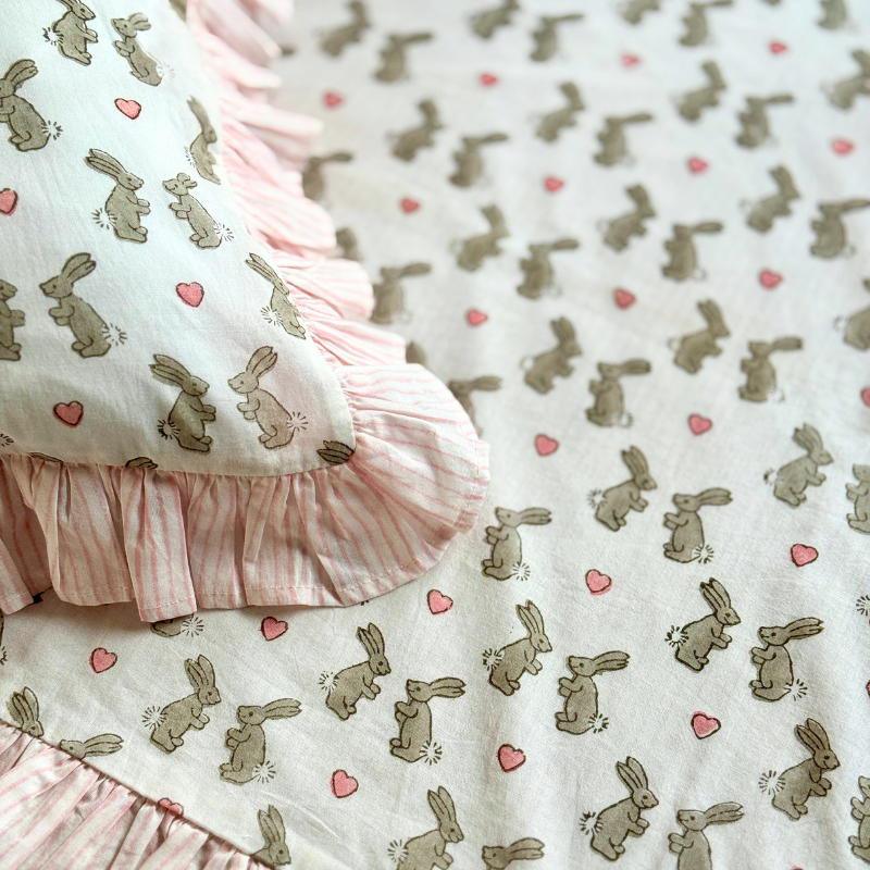 Unique single and cot size cotton duvet covers in pretty pale pink bunny block printed cotton with coordinating striped pink reverse and ruffle trim.