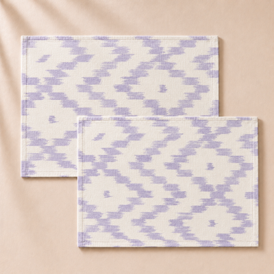 Two purple and white patterned placemats on a beige background